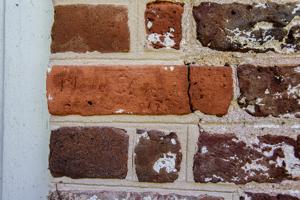 Graffiti carved into rubbed bricks framing window on teh front o